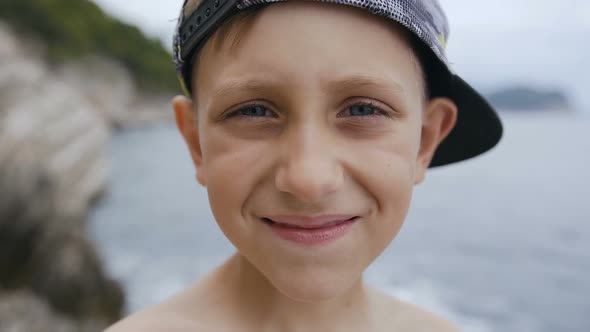 Portrait of a Cute Boy in a Peaked Cap Who Looking at the Camera