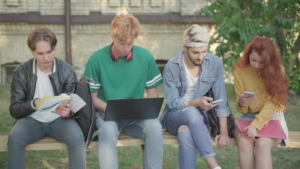 Four Concentrated University Students Surfing Internet and Doing Homework on Campus. Portrait of