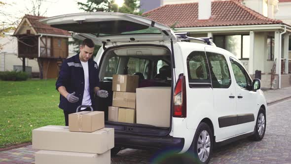 Young Handsome Caucasian Delivery Man Putting Boxes in Van Delivering Shipment