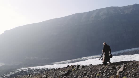 Travelling Man Hiking Down Rocky Hillside By Glacier