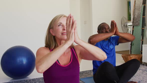 Diverse senior couple exercising practicing yoga together at home
