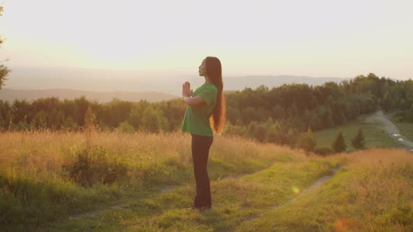 Serene Lovely Asian Female with Eyes Closed Meditating in Prayer Yoga Pose on Mountain Top at Dawn