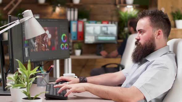 Cool Looking Bearded Videographer or Colorist Works on a Project