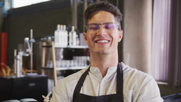 Portrait of happy caucasian man wearing apron working at a cafe bar, smiling to camera