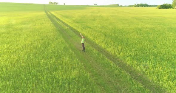 Sporty Child Standing in Green Wheat Field with Raised Hands Up. Evening Sport Training Exercises at