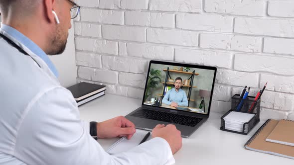 Doctor Wears Medical Coat in Hospital Consult Patient Online Video Call Laptop