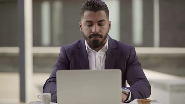 Serious Businessman Working with Laptop in Cafe