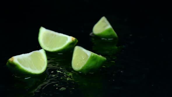 Lime Falls on the Table and Splits Into Pieces. Black Background. Slow Motion