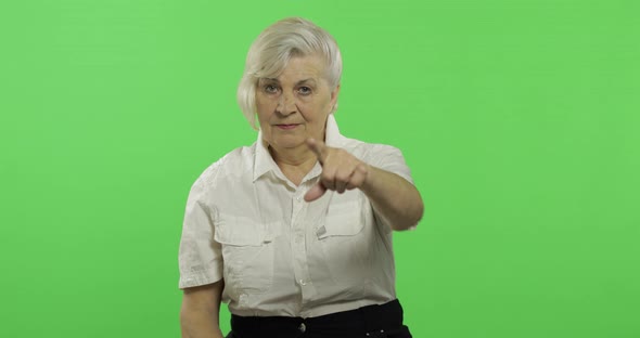 An Elderly Woman Points at the Camera and Smiles. Old Grandmother. Chroma Key