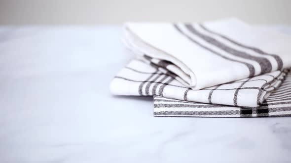 Folding black and white patterned paper towels on marble surface.