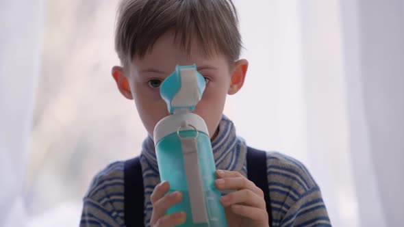 Front View Autistic Boy Drinking Water From Bottle Indoors at Home