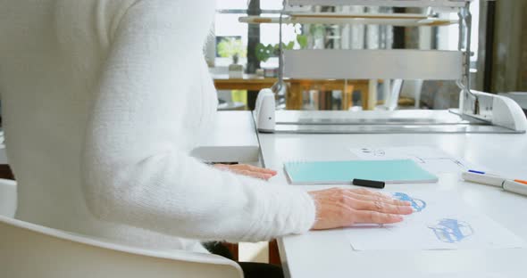 Car designers discussing over laptop at desk 