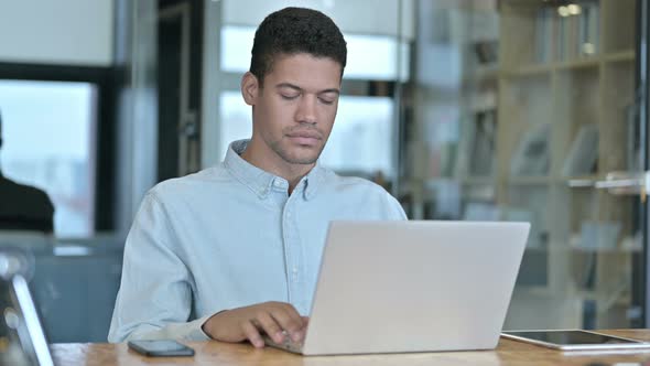 Young African Man Leaving Working Desk at Work