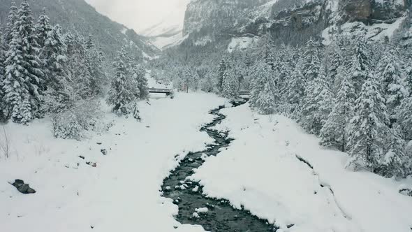 aerial of small creek running through snow covered landscape, drone slowly lifting up