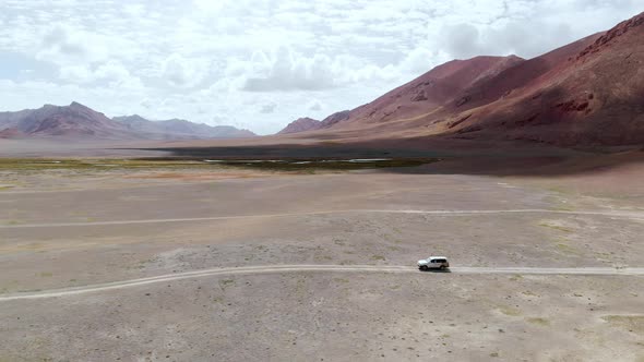 Aerial View of a Car Driving in a Dirt Road in the Tajikistan Desert