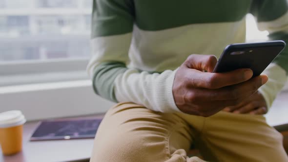 Businessman holding his phone while he is sitting on table