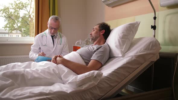 Elderly Doctor Talking To Sick Patient in Bed