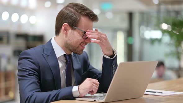 Businessman with Headache Using Laptop at Work 