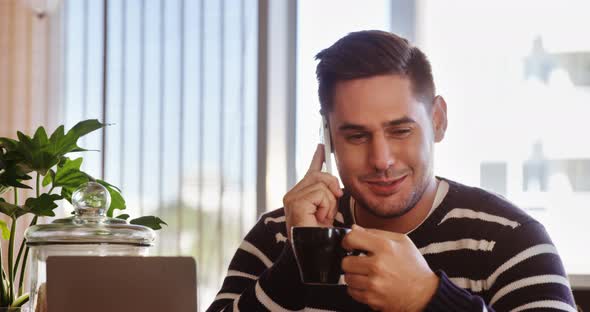 Man talking on mobile phone while having coffee