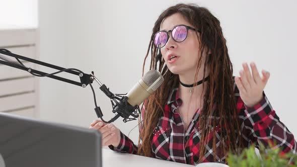 Concept of Streaming and Broadcasting. Young Cheerful Girl in the Studio Speaks Into a Microphone