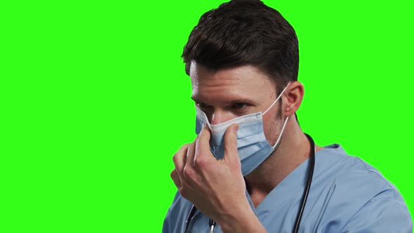 Caucasian male doctor wearing face mask on green screen background