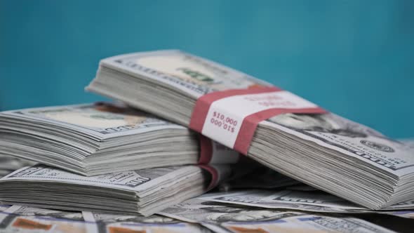 Bundles of Dollars Lying on a Pile of Money and Rotate on Blue Background