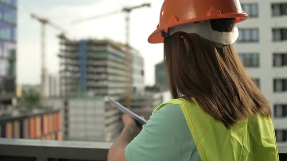 Female Builder in a Signal Vest and Helmet Writes Something