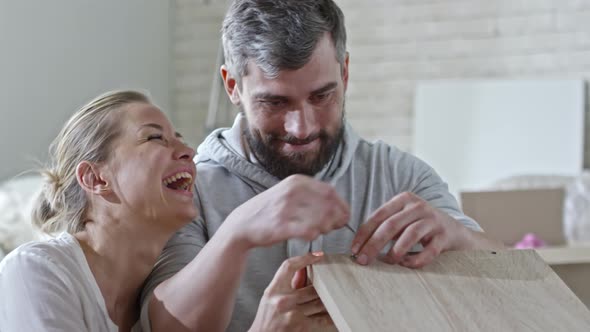 Woman Helping Man Assembling Shelf alt