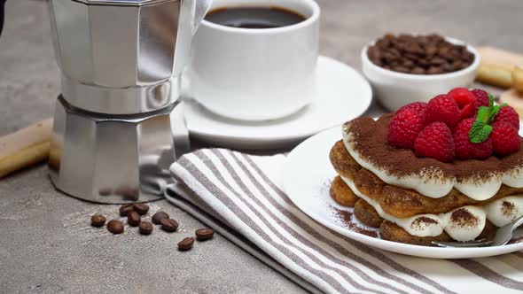 Portion of Classic Tiramisu Dessert with Berries, Espresso, Coffee Maker on Grey Concrete Background