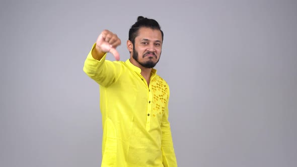 Annoyed Indian man showing thumbs down in an Indian outfit