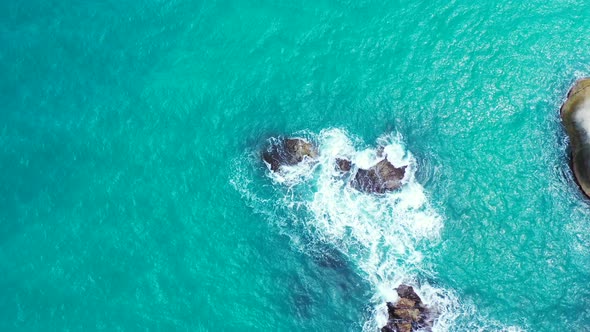 Vertical tropical turquoise sea background. Waves crashing on the rocks on sunny summer day