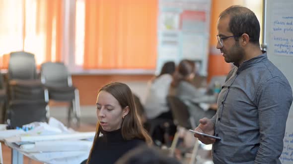 Man Helps Woman Colleague with Conference Seminar Preparation