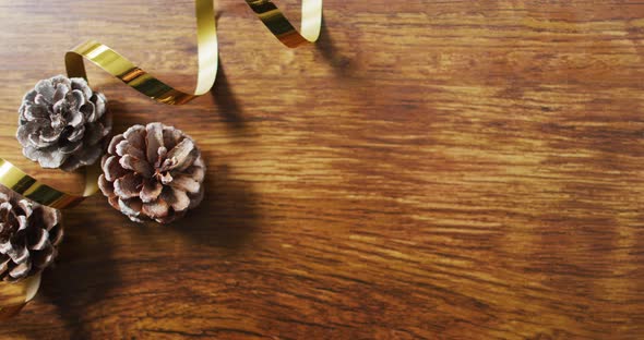 Video of christmas decorations with pine cones and copy space on wooden background
