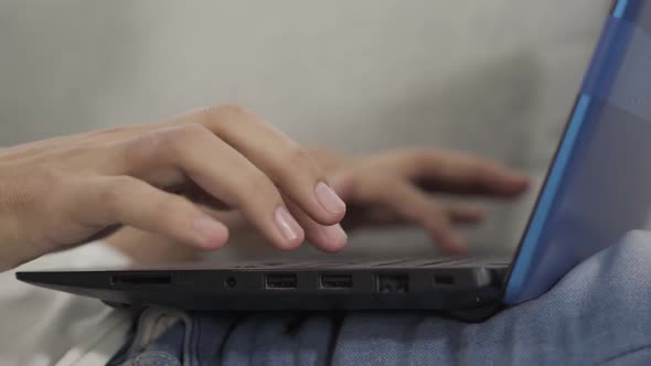 Side View Close-up of Male Caucasian Hands Typing on Laptop Keyboard. Unrecognizable Young Man