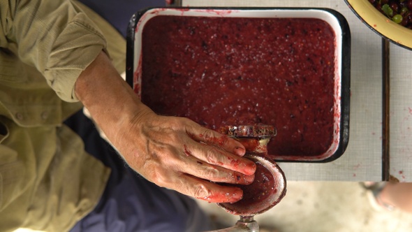 Man's hands chops summer berries for jam in grinder closeup