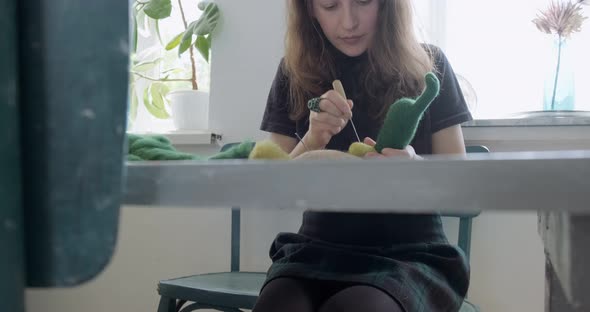 Woman Making Wool Art Doll Toy at Table. Female Sitting and Creating Ooak Doll at Home. Needle