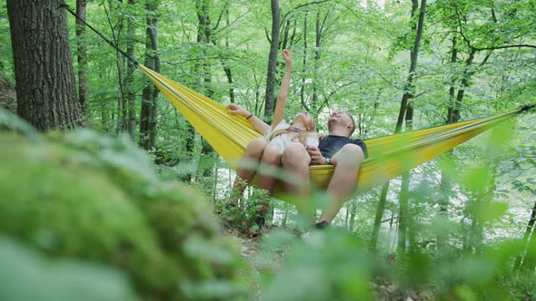 Couple relaxing in a hammock and pointing up