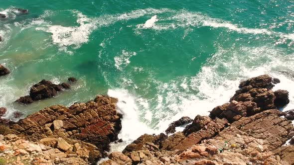 Rocky Coastline with turqoise waves breaking into rocks, aerial drone view.