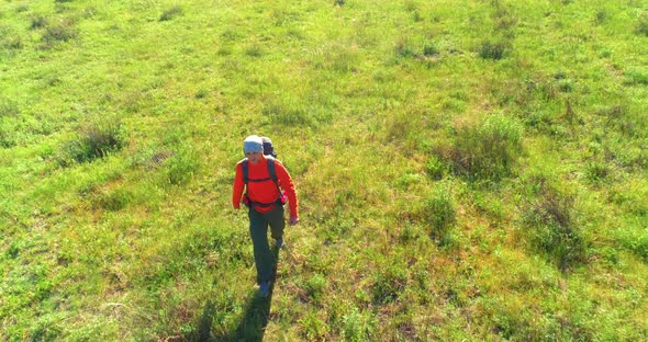 Flight Over Backpack Hiking Tourist Walking Across Green Mountain Field. Huge Rural Valley at Summer