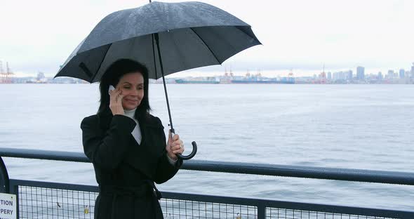 Woman holding umbrella and talking on mobile phone