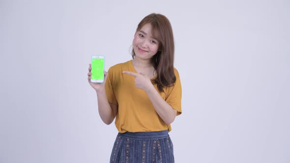 Happy Young Beautiful Asian Woman Showing Phone and Giving Thumbs Up