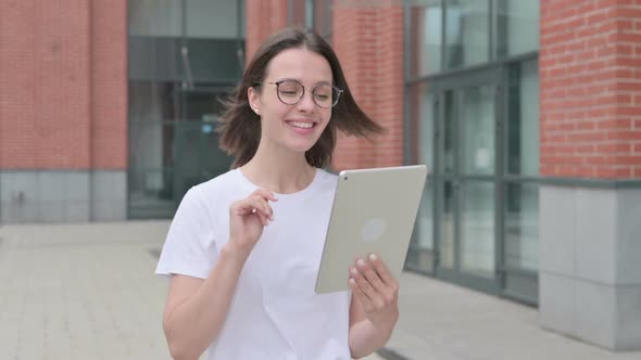 Young Woman making Video Call on Tablet while Walking on Street