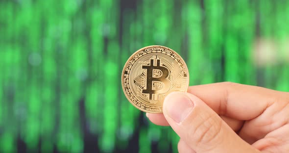 Hand Holding Bitcoin Over Green Background