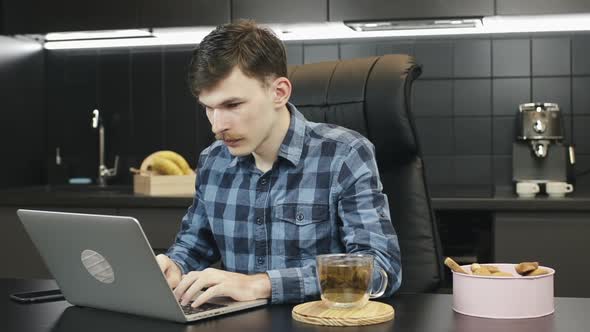 Young man works on laptop computer at home