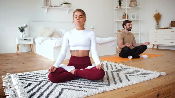 Young Happy Caucasian Couple Doing Lotus Pose Practice in Cozy Bedroom at Home Slow Motion