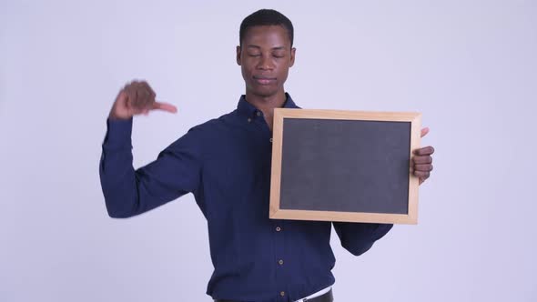 Young Stressed African Businessman Holding Blackboard and Giving Thumbs Down