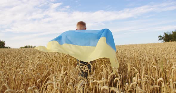 A Child Runs Through a Wheat Field Holding a Ukrainian Flag