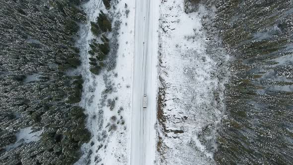Aerial shot over the forest road between mountains in winter in Alberta, Canada