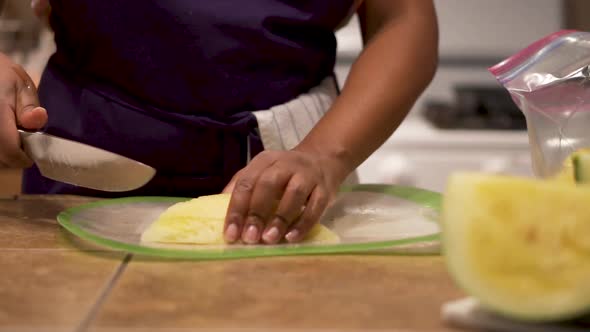 Close up, black female hands cutting yellow watermelon