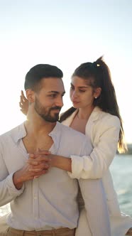 Hispanic Woman Kissing Boyfriend on Embankment in Sunshine